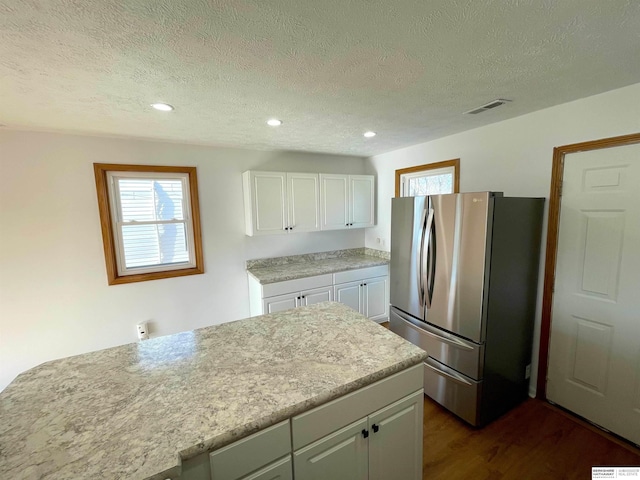 kitchen featuring white cabinetry, stainless steel fridge, and a textured ceiling