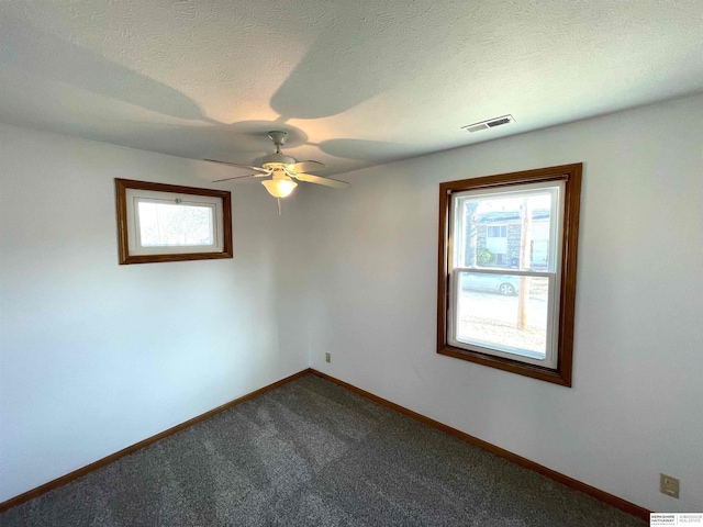 carpeted spare room featuring ceiling fan and a textured ceiling