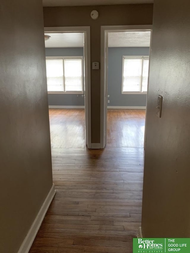 hallway featuring baseboards and wood finished floors