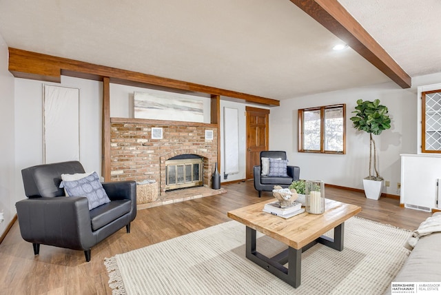 living room with wood-type flooring, a brick fireplace, and beam ceiling