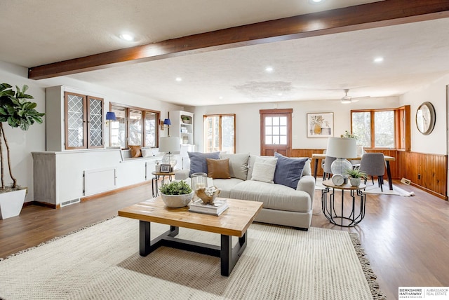 living room featuring hardwood / wood-style flooring, ceiling fan, a textured ceiling, and wood walls