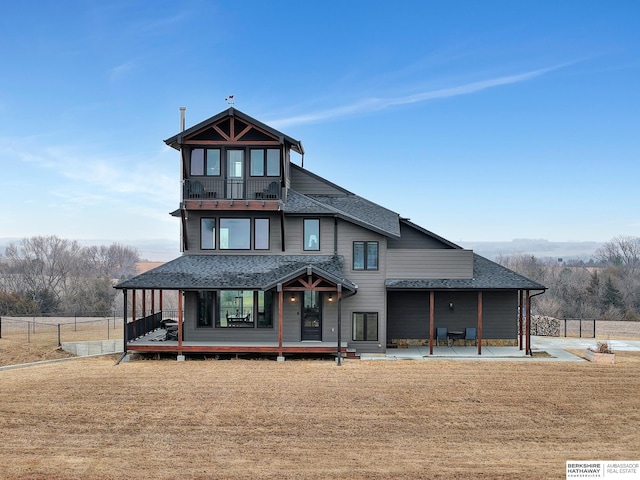 back of house featuring a balcony, a patio area, and a lawn