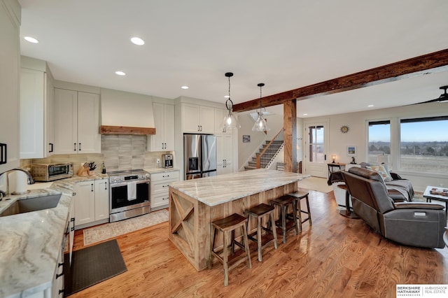 kitchen with premium range hood, sink, white cabinetry, appliances with stainless steel finishes, and pendant lighting