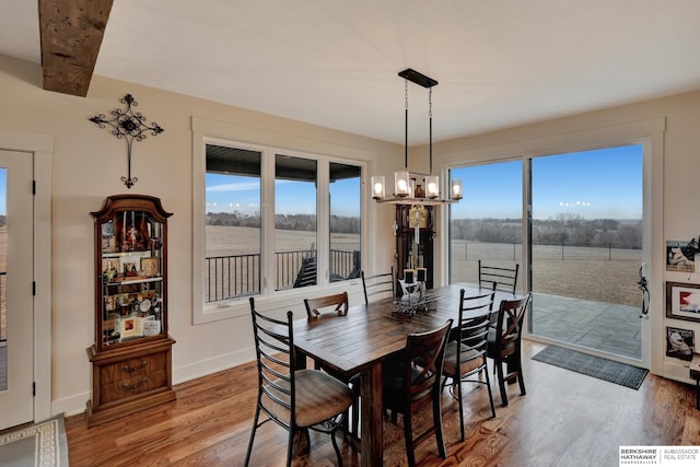 dining area featuring hardwood / wood-style flooring, an inviting chandelier, and beamed ceiling