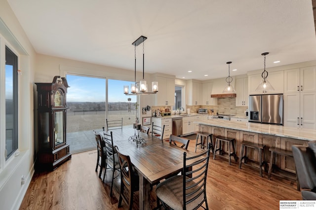 dining area featuring sink, light hardwood / wood-style flooring, and a chandelier