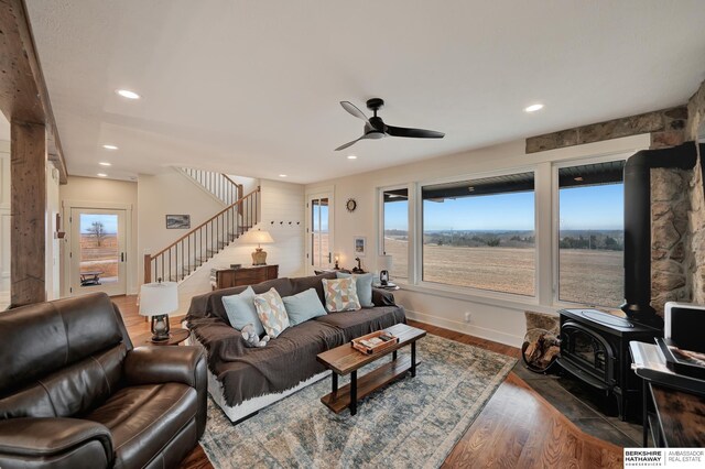 living room featuring dark hardwood / wood-style flooring, ceiling fan, and a wood stove