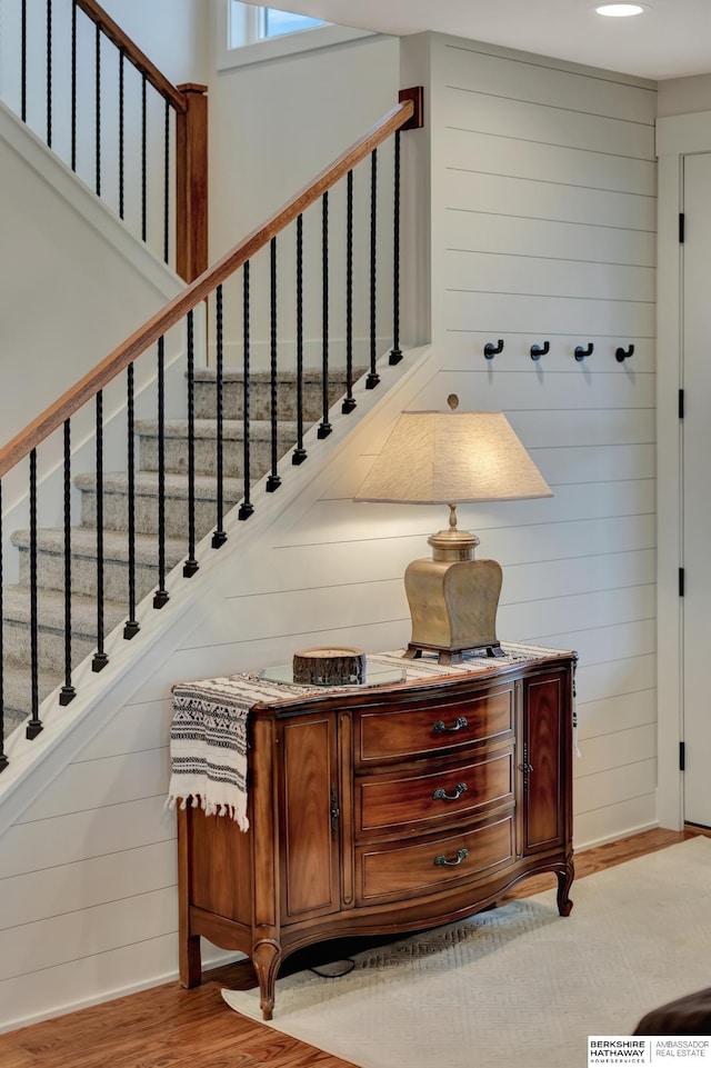 stairs featuring wood-type flooring and wood walls