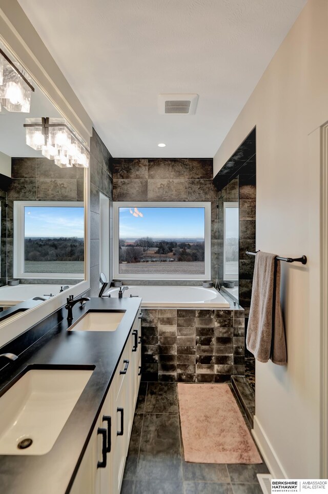 bathroom featuring vanity and tiled tub