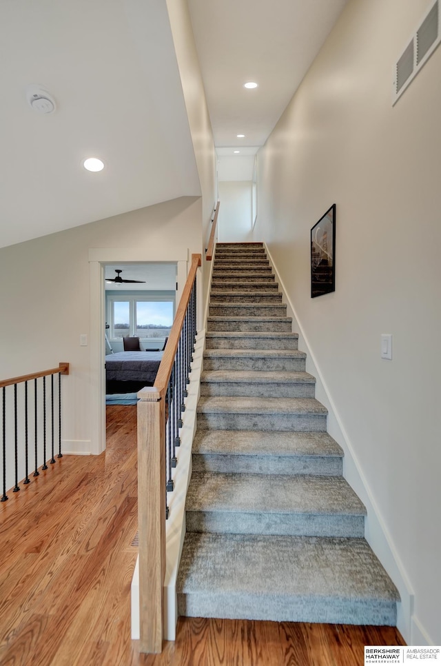 stairs featuring hardwood / wood-style flooring and vaulted ceiling