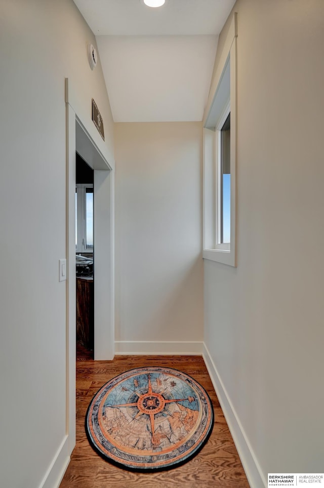 hallway with hardwood / wood-style flooring and vaulted ceiling