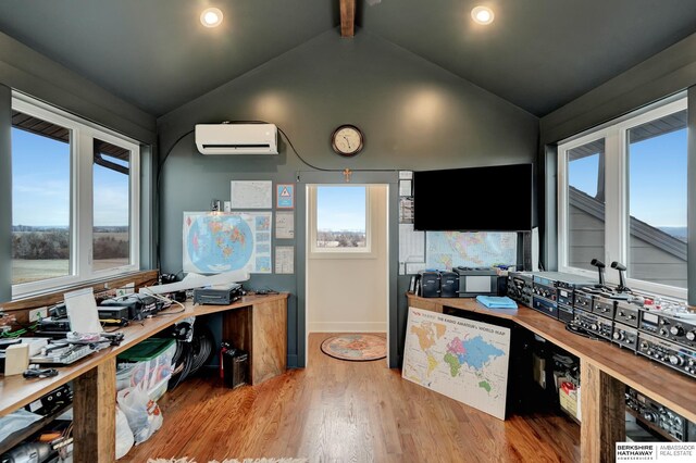 home office featuring light hardwood / wood-style floors, a wall unit AC, and vaulted ceiling with beams