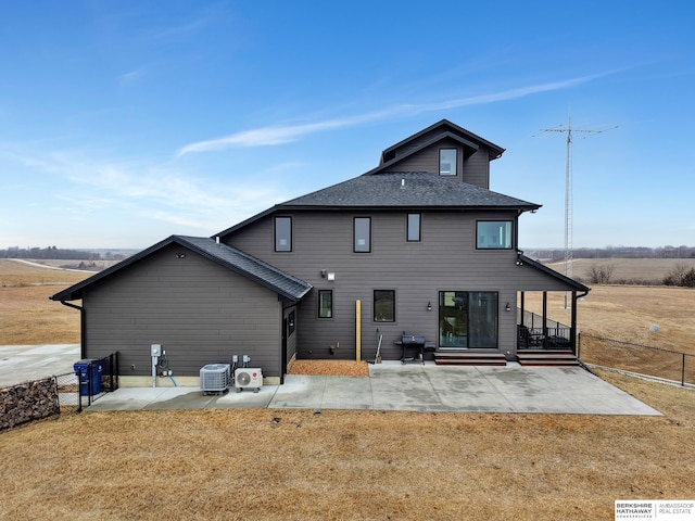 back of house with a rural view, a lawn, a patio, and central air condition unit