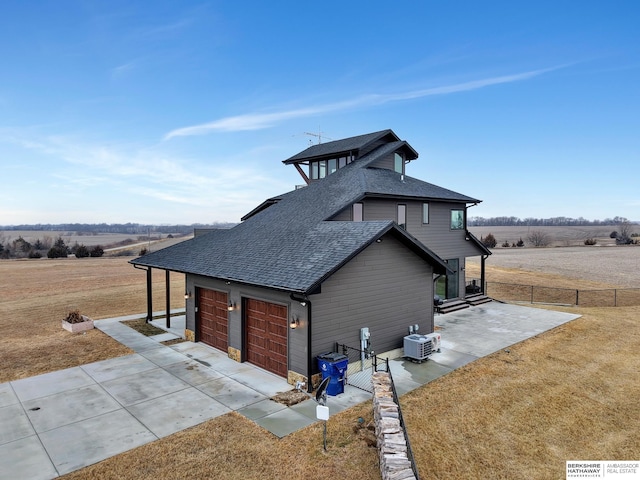 view of home's exterior featuring a garage, a yard, and a rural view