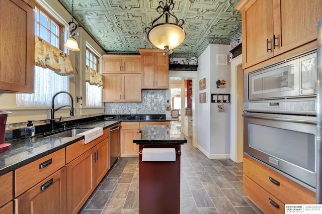 kitchen featuring sink, tasteful backsplash, dark stone countertops, pendant lighting, and stainless steel appliances