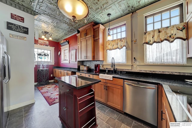 kitchen with a kitchen island, sink, hanging light fixtures, stainless steel dishwasher, and a healthy amount of sunlight