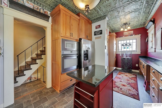 kitchen featuring stainless steel appliances, a kitchen island, and dark stone countertops