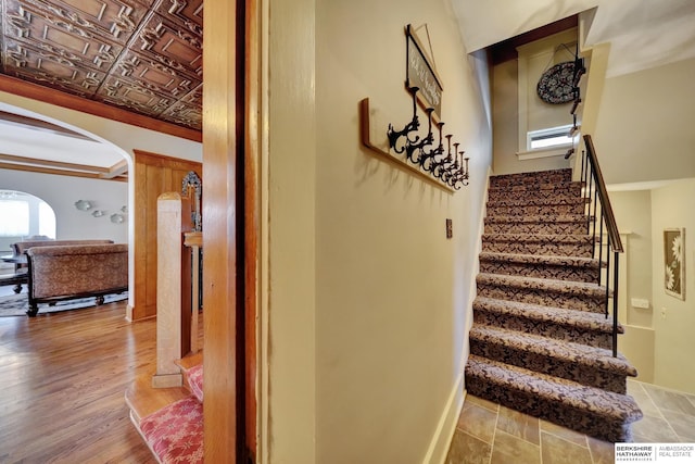 staircase with ornamental molding and hardwood / wood-style floors