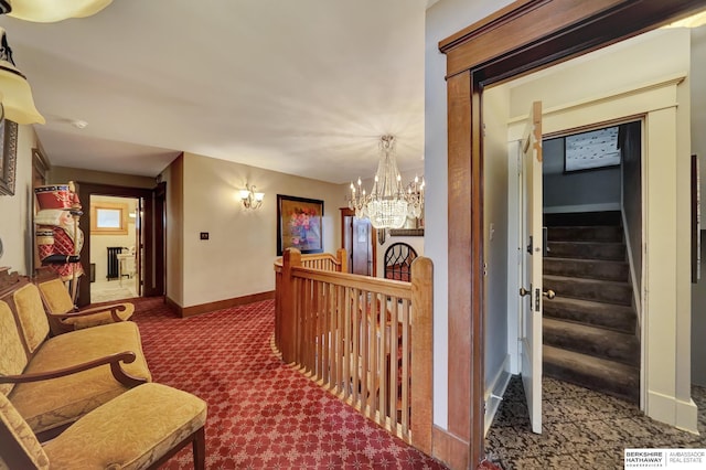 hallway with an inviting chandelier and dark colored carpet