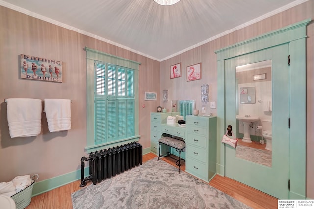 interior space with radiator, hardwood / wood-style floors, sink, ornamental molding, and toilet