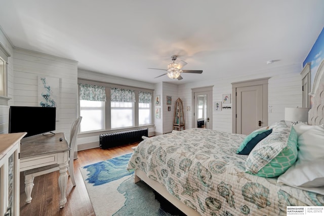 bedroom featuring ceiling fan, radiator heating unit, and wood-type flooring