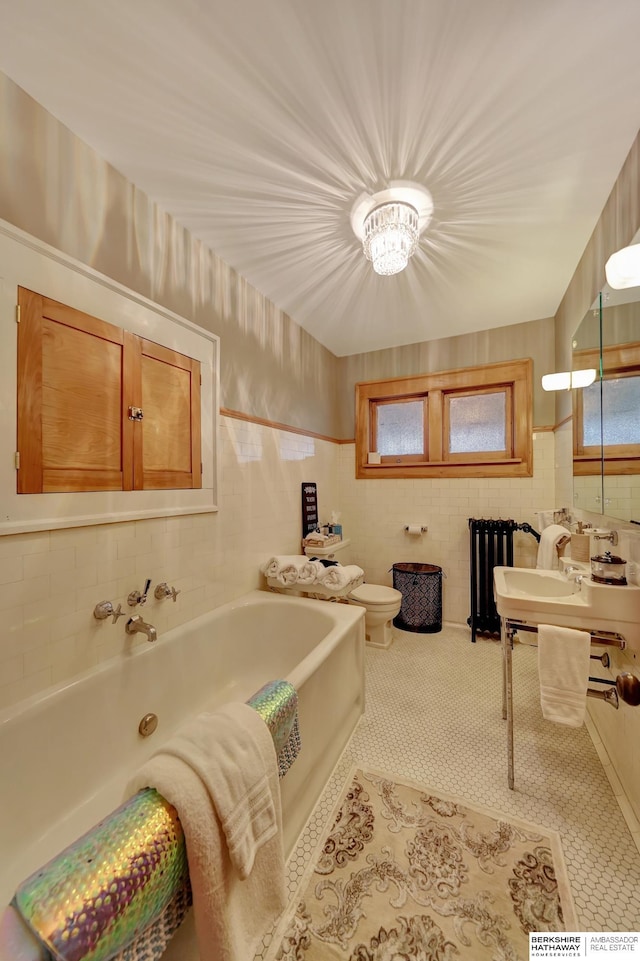 bathroom featuring toilet, tile patterned flooring, tile walls, and a bath