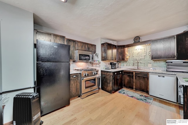 kitchen featuring sink, decorative backsplash, dark brown cabinetry, stainless steel appliances, and light wood-type flooring