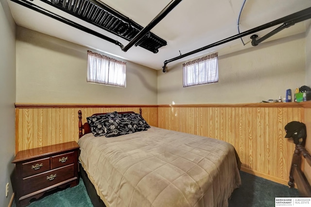 carpeted bedroom featuring multiple windows and wood walls