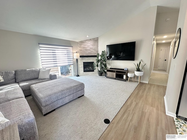 living room featuring lofted ceiling, a fireplace, and light hardwood / wood-style flooring