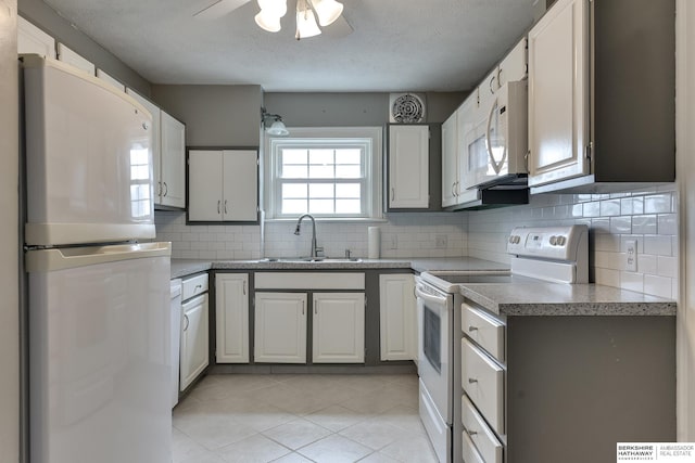 kitchen with light tile patterned flooring, sink, white cabinetry, white appliances, and decorative backsplash