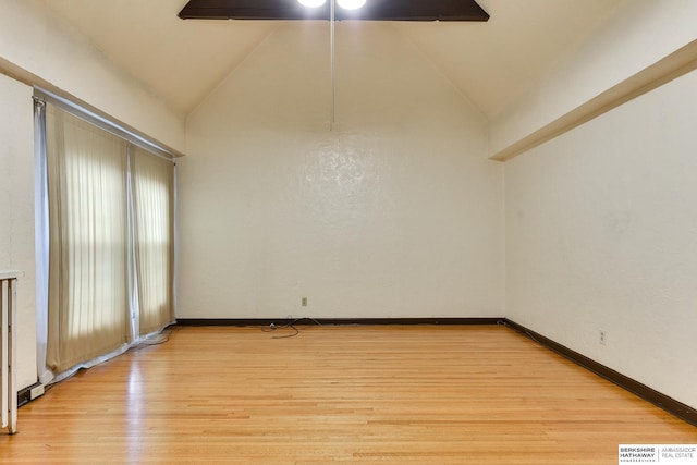 spare room with lofted ceiling and light wood-type flooring