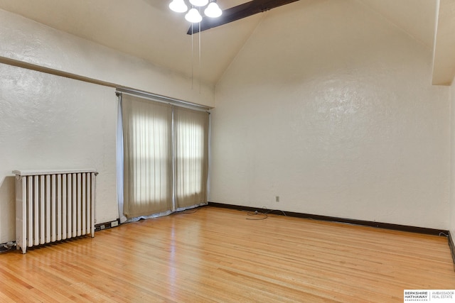 spare room featuring radiator, light hardwood / wood-style floors, and high vaulted ceiling