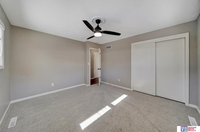 unfurnished bedroom featuring light carpet, baseboards, visible vents, and a closet