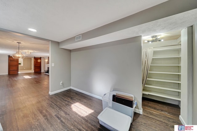 interior space featuring dark wood-type flooring, visible vents, baseboards, and a barn door