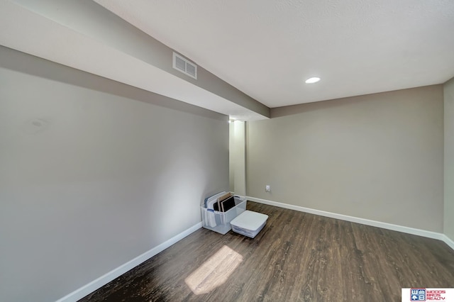 finished basement featuring baseboards, visible vents, and dark wood-style flooring