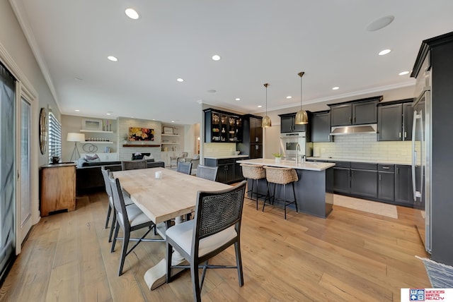 dining area featuring crown molding, a large fireplace, and light wood-type flooring