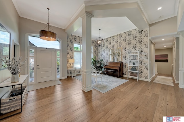 foyer with light hardwood / wood-style flooring, ornamental molding, and ornate columns