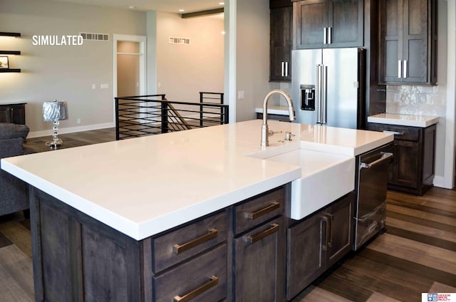 kitchen with stainless steel appliances, sink, a center island with sink, and dark hardwood / wood-style floors