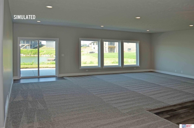 unfurnished room featuring carpet flooring and a water view