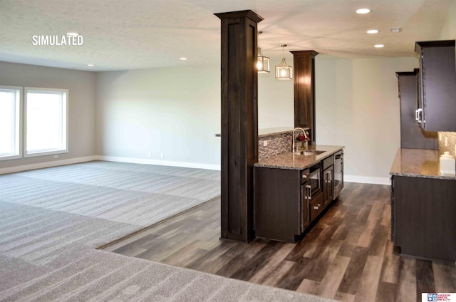 kitchen featuring decorative columns, sink, dark hardwood / wood-style flooring, hanging light fixtures, and dark brown cabinetry