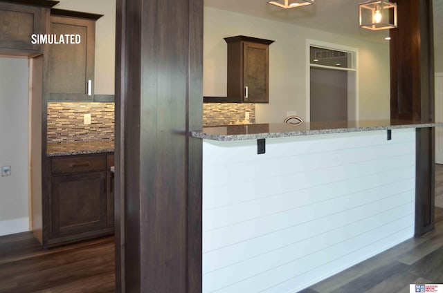 kitchen featuring dark stone countertops, backsplash, a kitchen breakfast bar, and kitchen peninsula