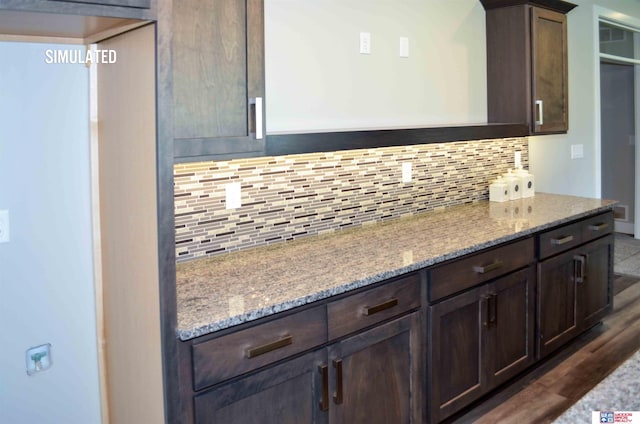 kitchen featuring tasteful backsplash, dark hardwood / wood-style flooring, light stone countertops, and dark brown cabinets