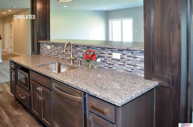 kitchen featuring stainless steel appliances, dark hardwood / wood-style flooring, sink, and light stone counters