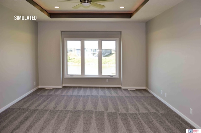 carpeted empty room featuring a raised ceiling and ceiling fan