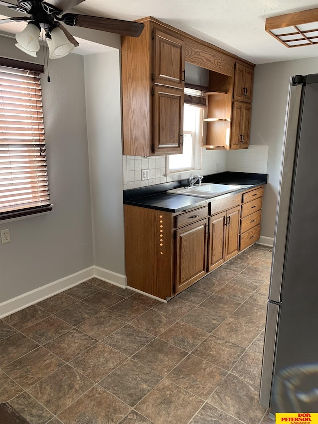 kitchen with stainless steel refrigerator, ceiling fan, sink, and decorative backsplash