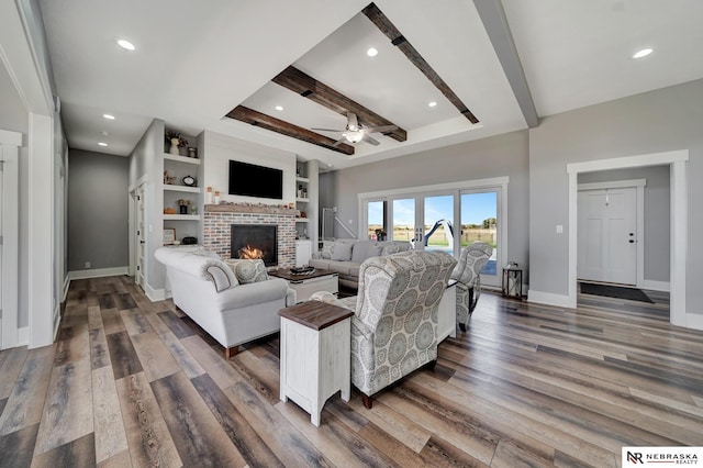 living room featuring a brick fireplace, built in features, dark hardwood / wood-style floors, and beamed ceiling