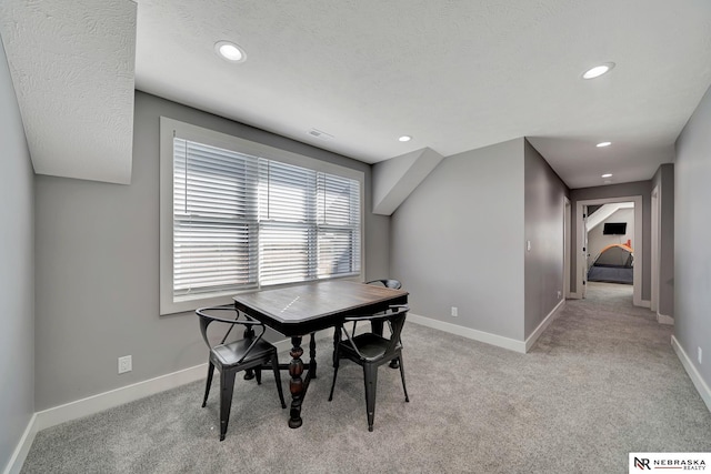 dining area with light colored carpet and a textured ceiling