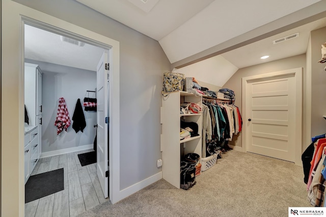 walk in closet featuring vaulted ceiling and light hardwood / wood-style floors