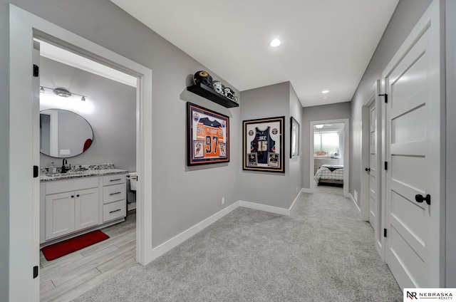 hallway featuring sink and light carpet