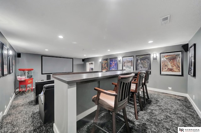 home theater room with indoor bar and dark carpet