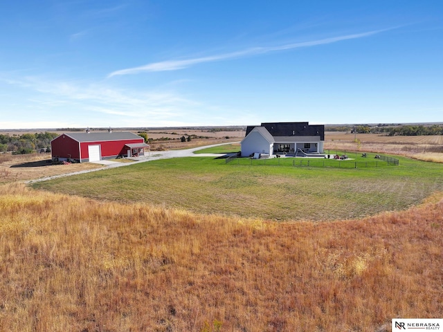 view of yard featuring a rural view, a garage, and an outbuilding